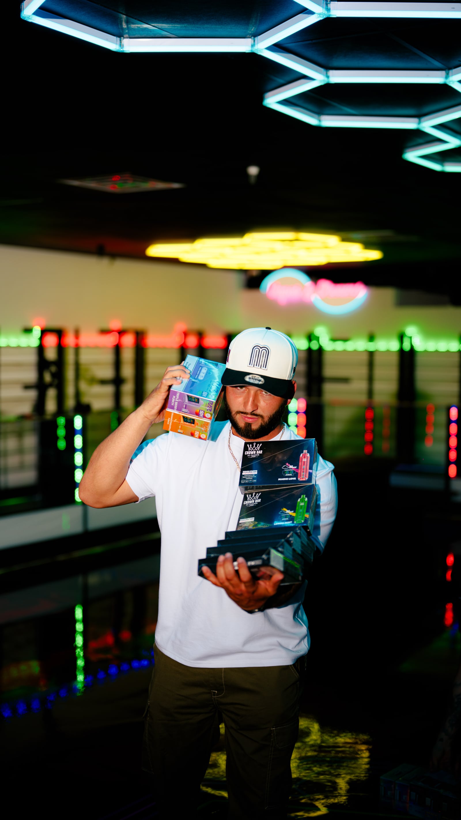 A man holding boxed products among illuminated display counters inside Zona Verde.